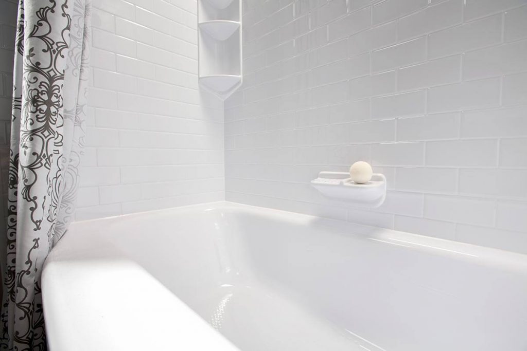 Clean white acrylic bathtub with a soap holder