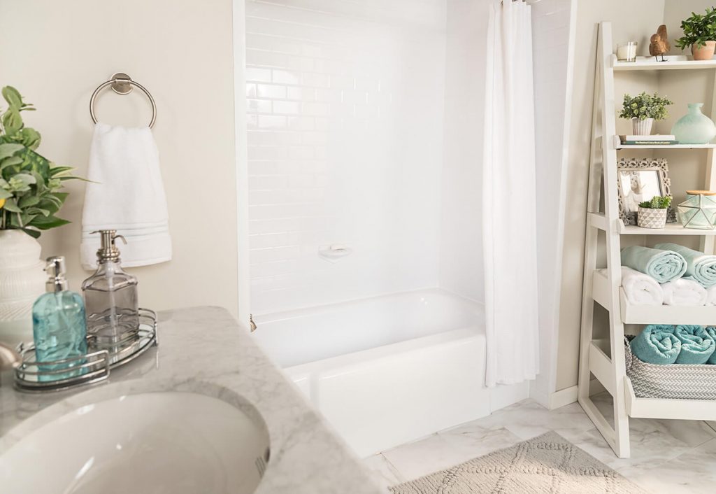 A cream-colored bathroom with a white tub and marble vanity